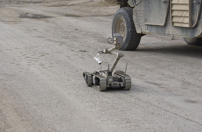 i-Robot carries a stick of C4 plastic explosives down the street to an alleged improvised explosive device
